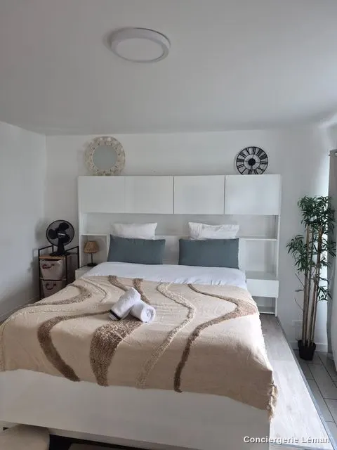 Chambre blanche : lit fait avec plaid et serviettes roulées