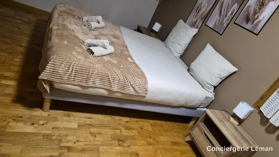 Chambre aux tons sable : lit fait, deux jeux de serviettes posés